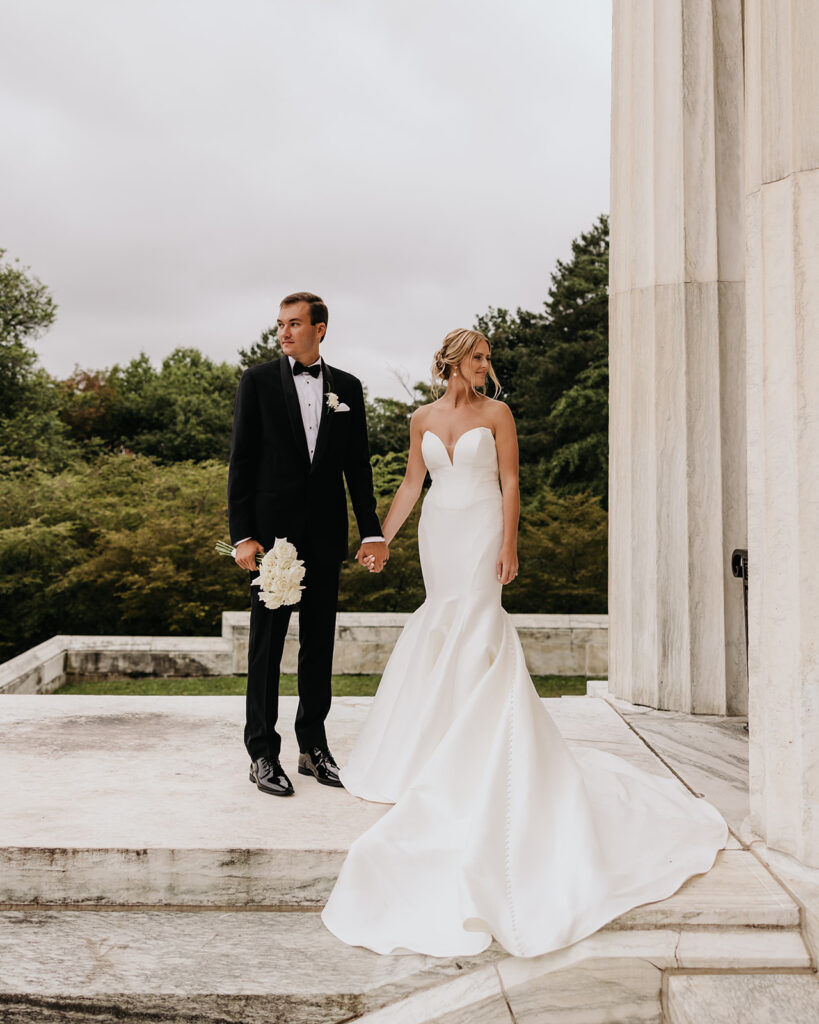A timeless modern wedding in Upstate New York. The couple stands side by side next to the white columns of the Buffalo History Museum
