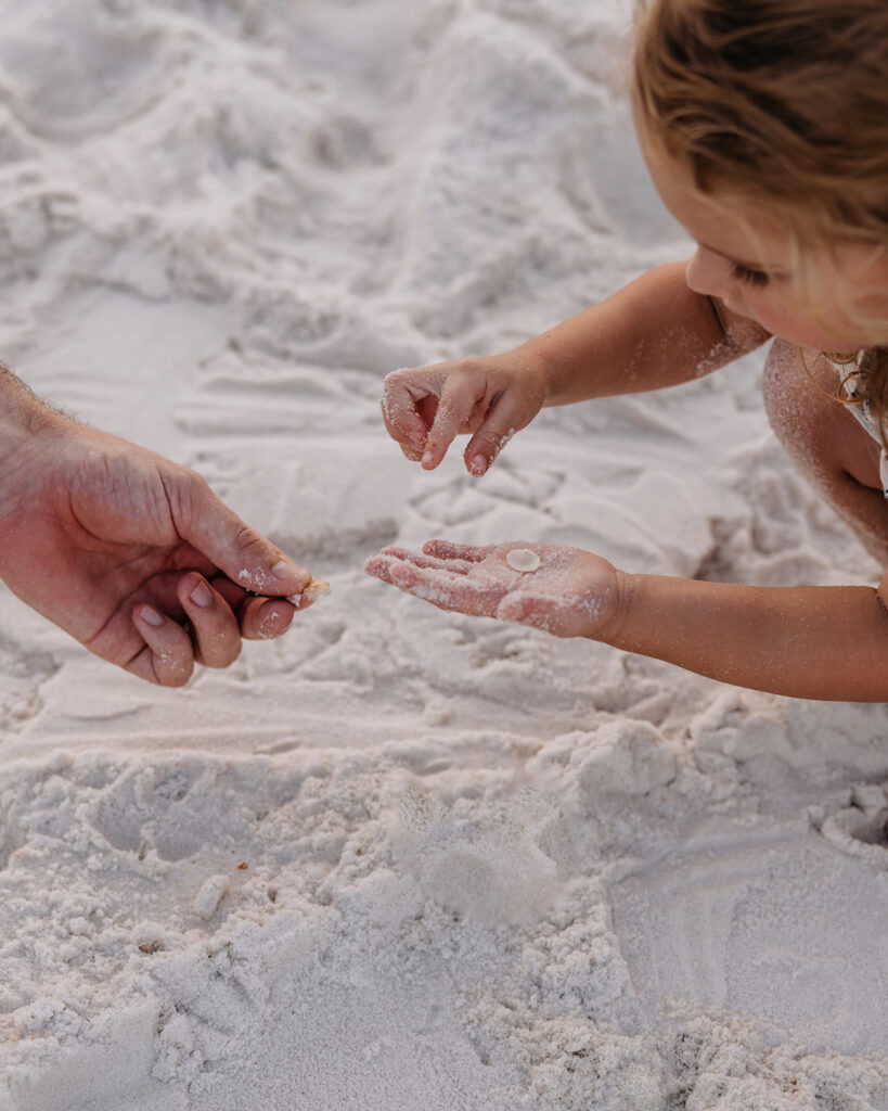 little girl digs through the beach sand