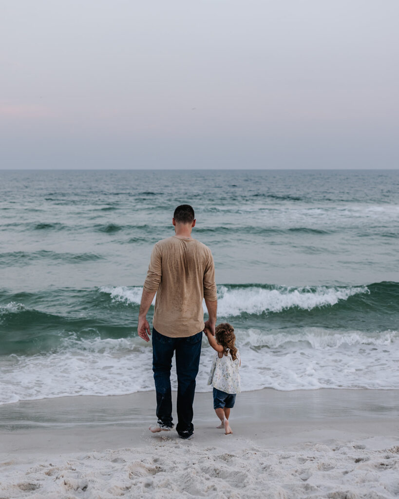 father and daughter walk on the beach