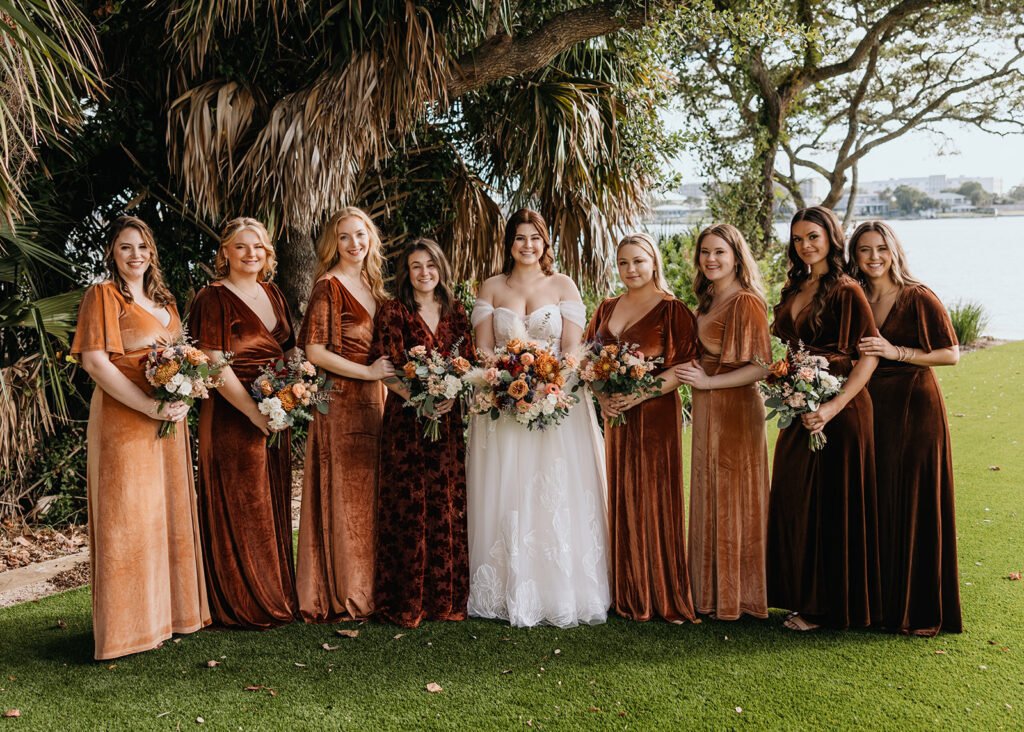 bride and bridesmaids smile while holding bouquets