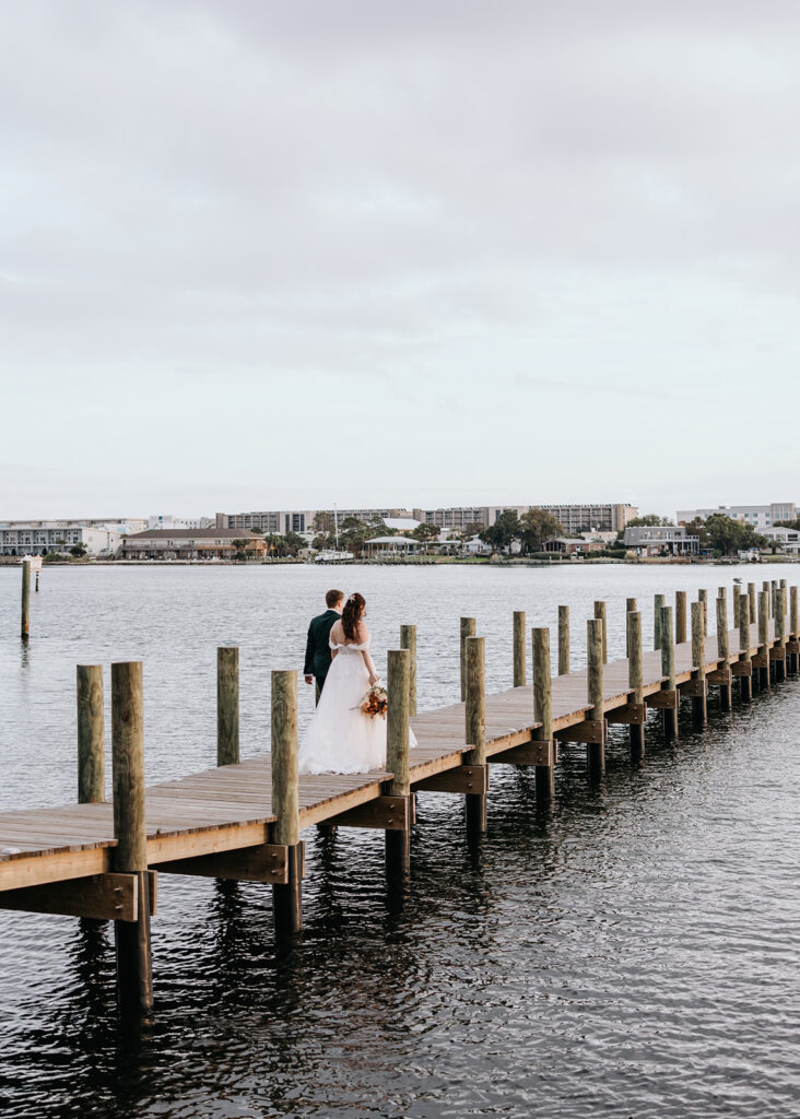 bride and groom walk on a dock