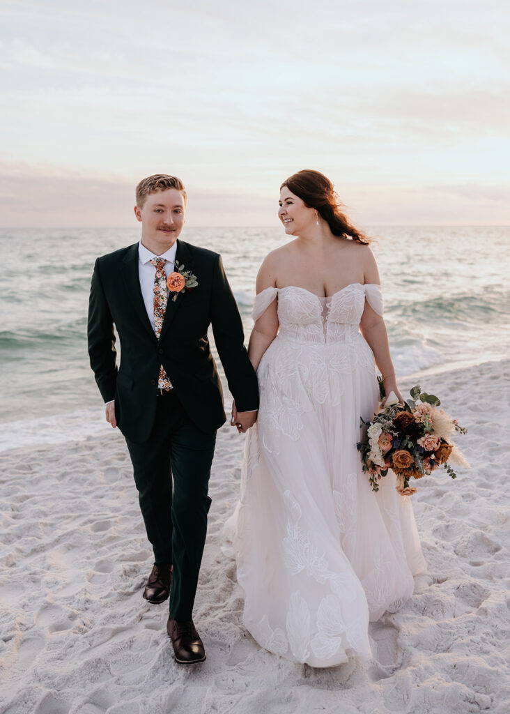 bride and groom walk on the beach