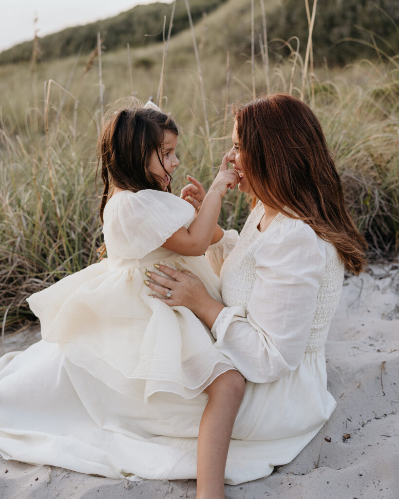 a mother and daughter play in the sand