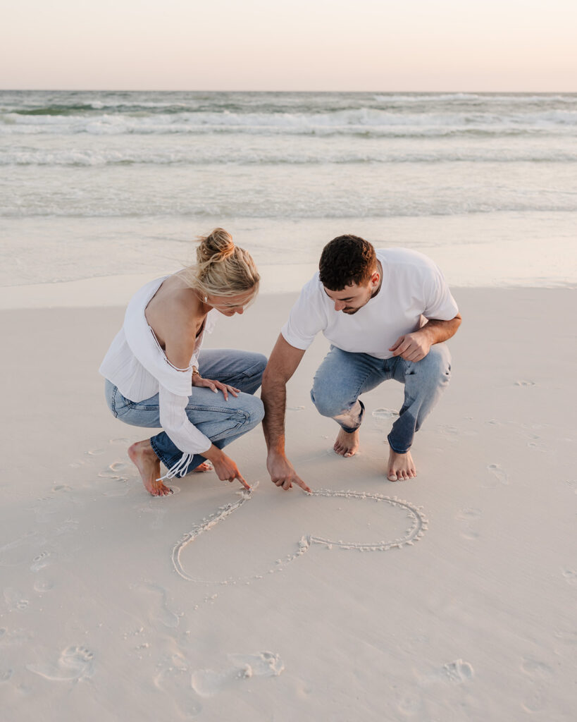man and woman draw a heart in the sand