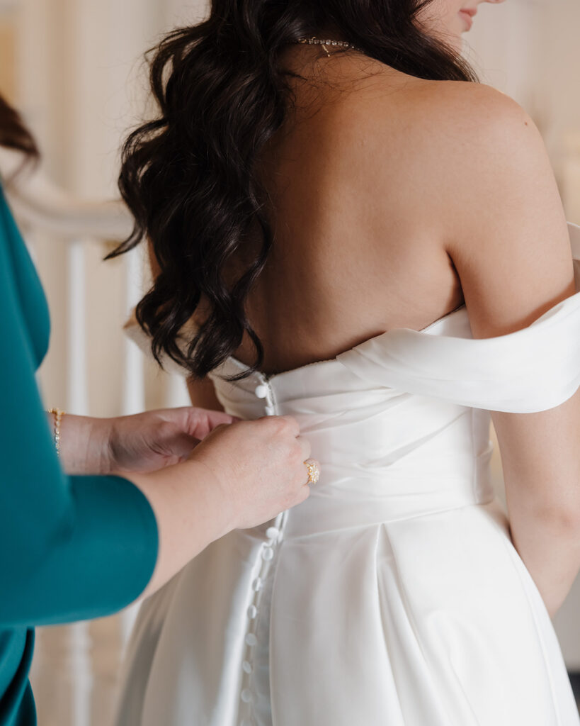 mom zips up the bride's dress