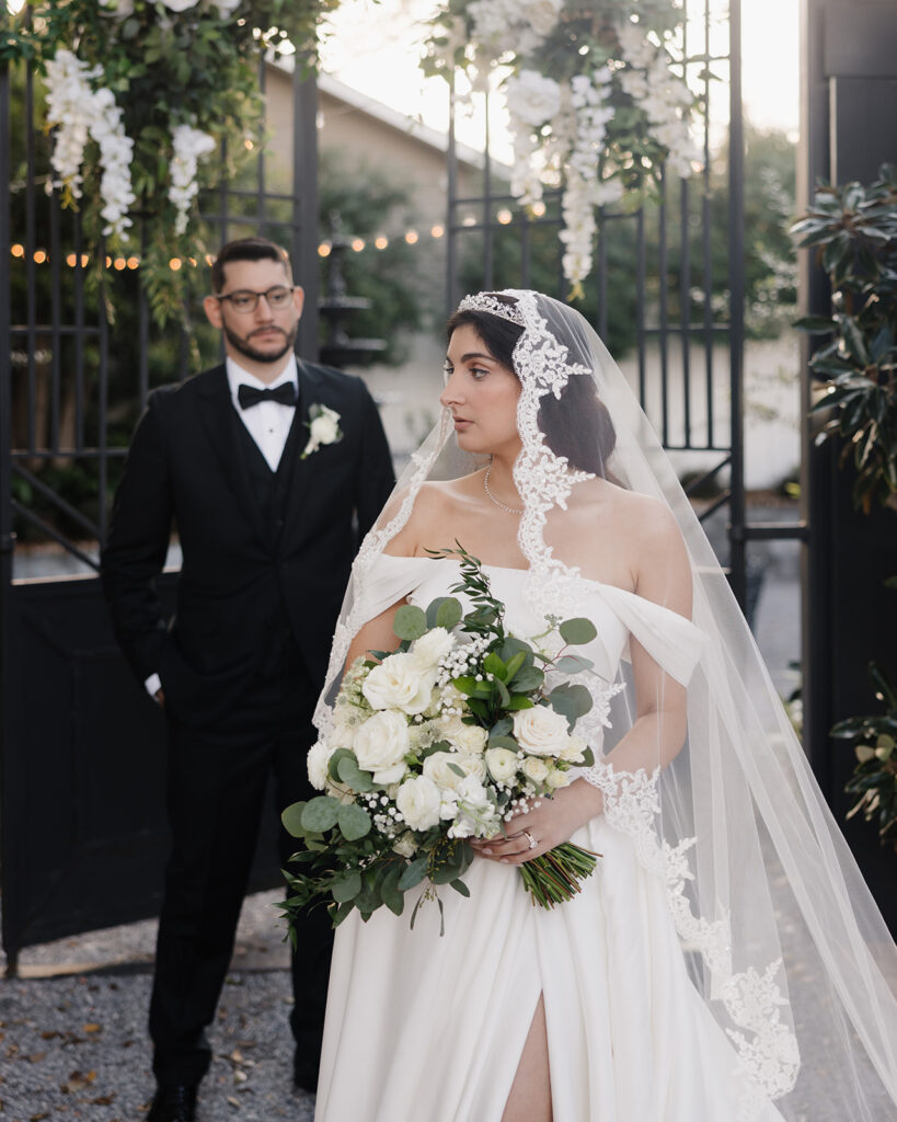 bride looks into the distance as groom admires her