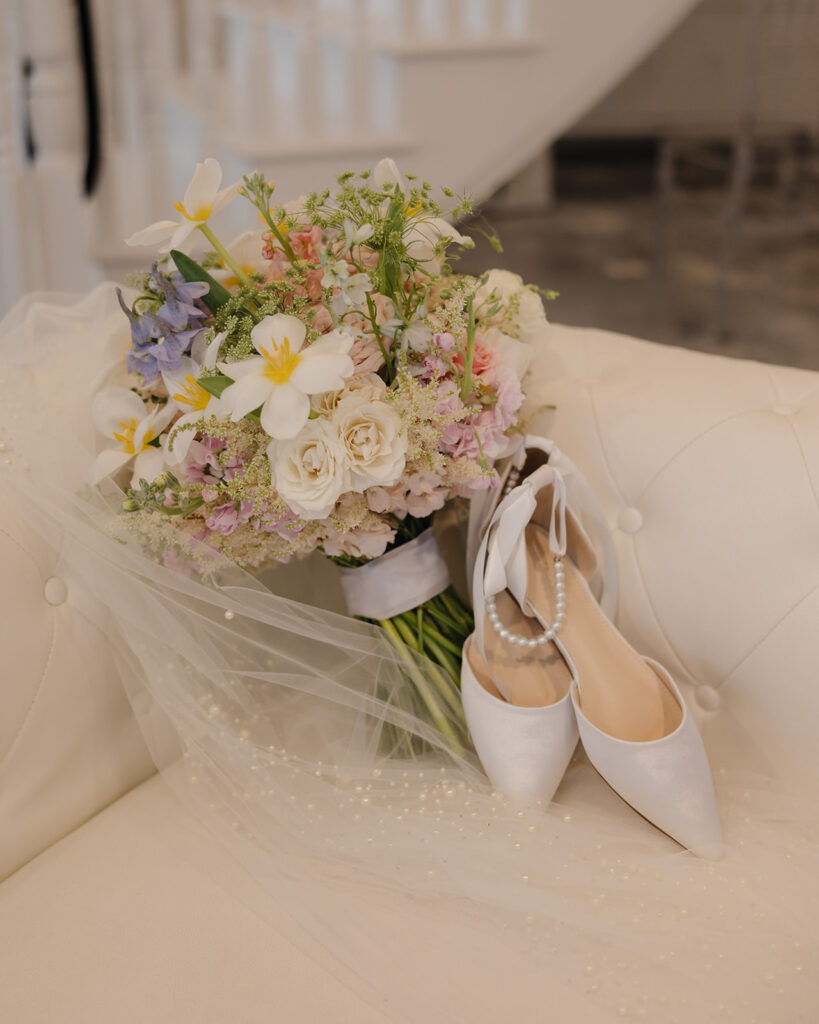 bride's bouquet and shoes laid on a couch