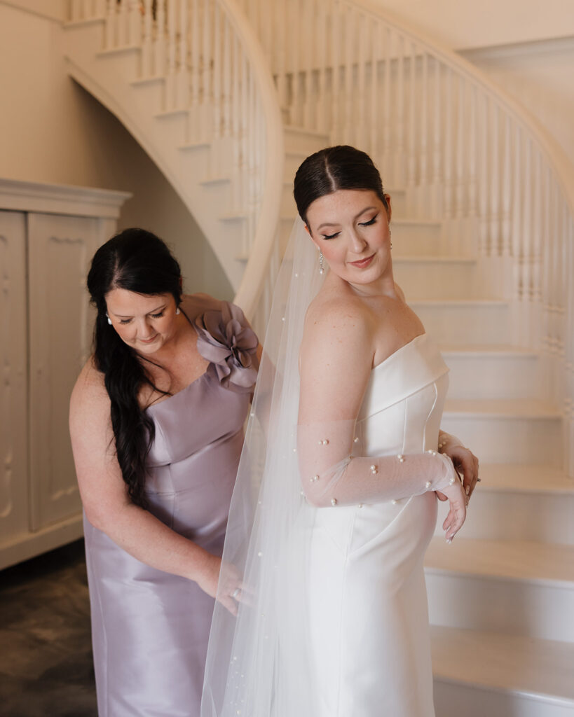 mother zips up the bride's dress