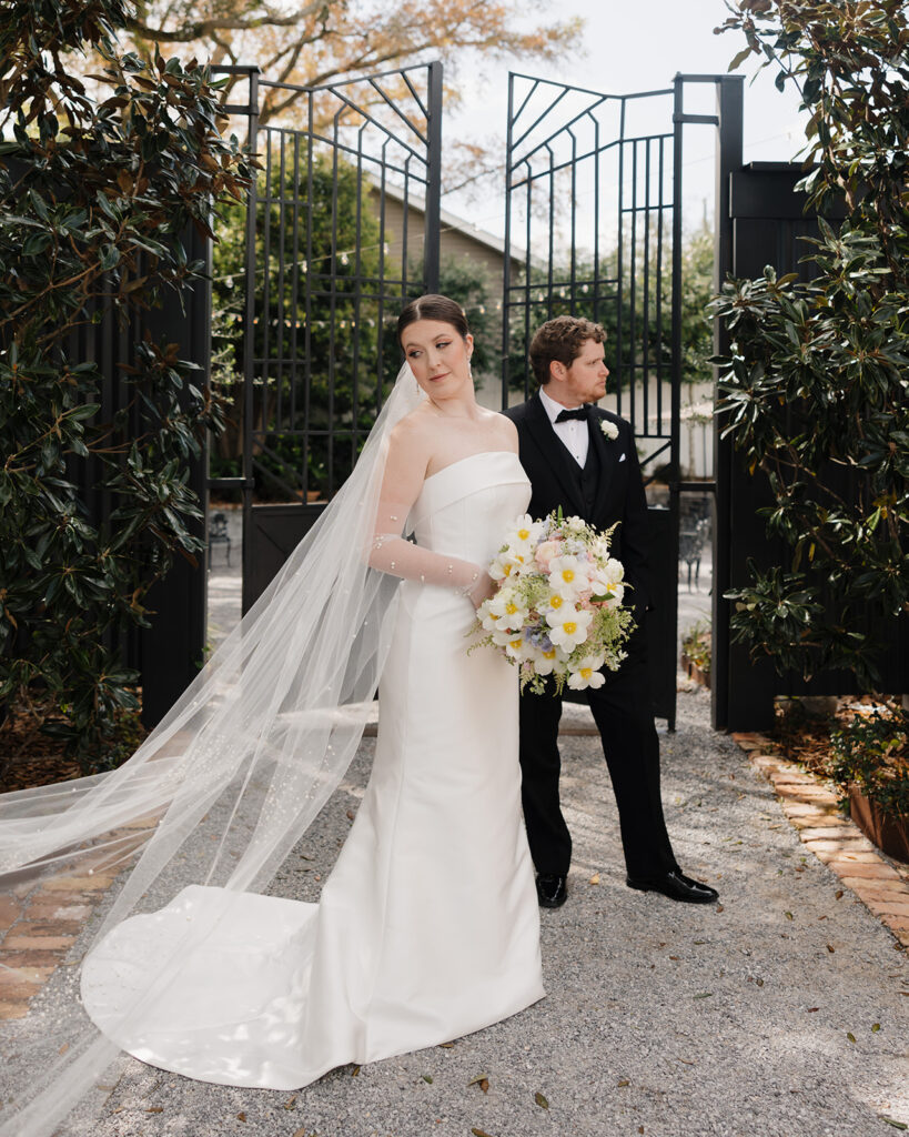 A bride and groom stand by the gate at Supposey Warehouse and Gardens
