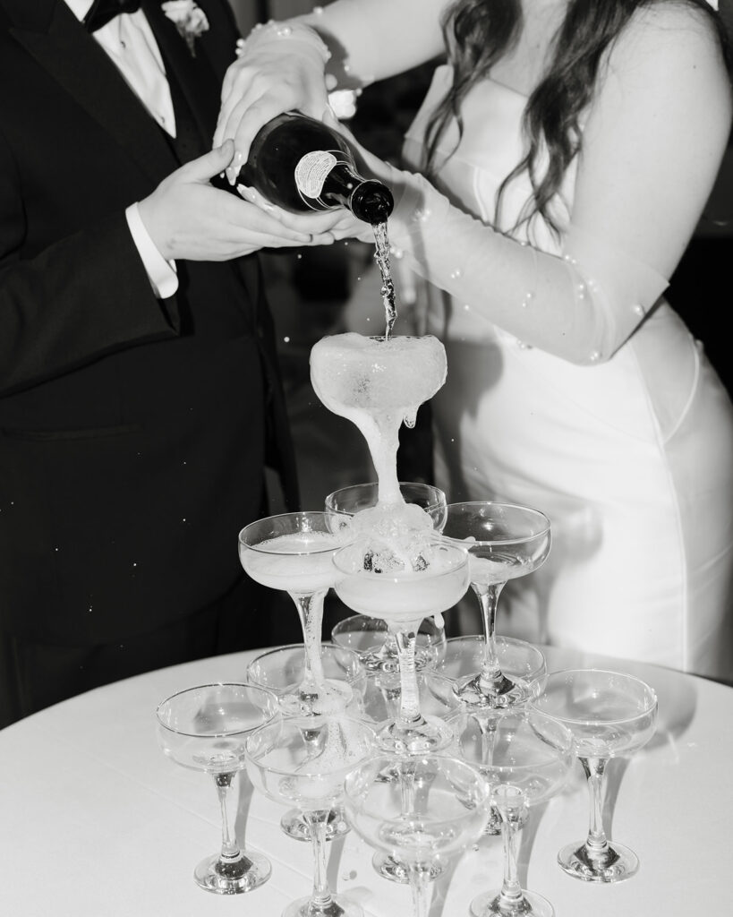 man and woman pour champagne into a tower