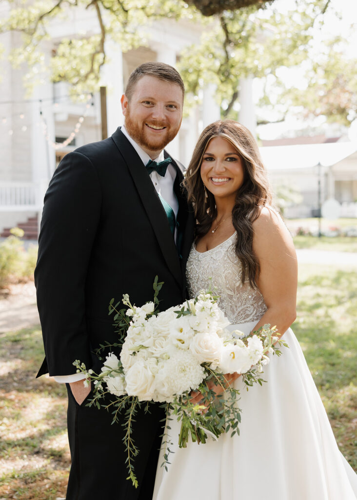 bride and groom smile outside of the Pillars Venue in Mobile, AL