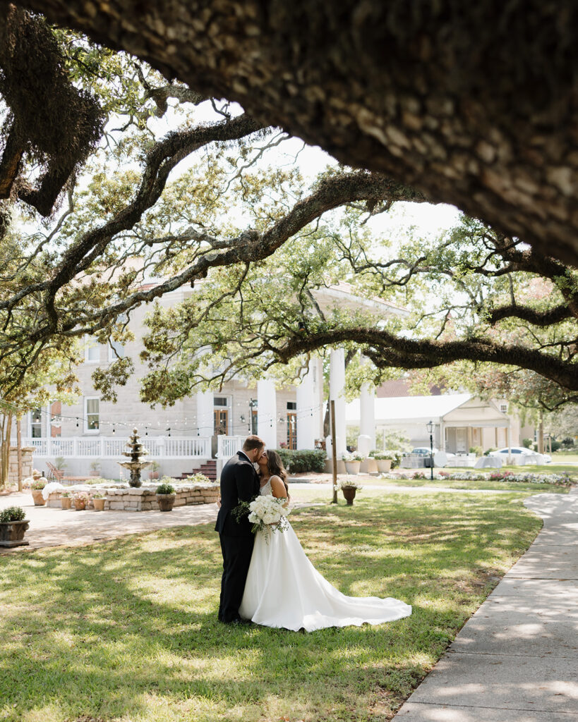 bride and groom kiss in the garden of the Pillars Venue in Mobile, AL