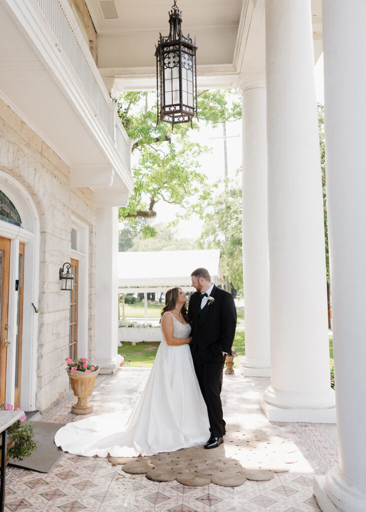 bride and groom smile at each other outside of the Pillars Venue in Mobile, AL
