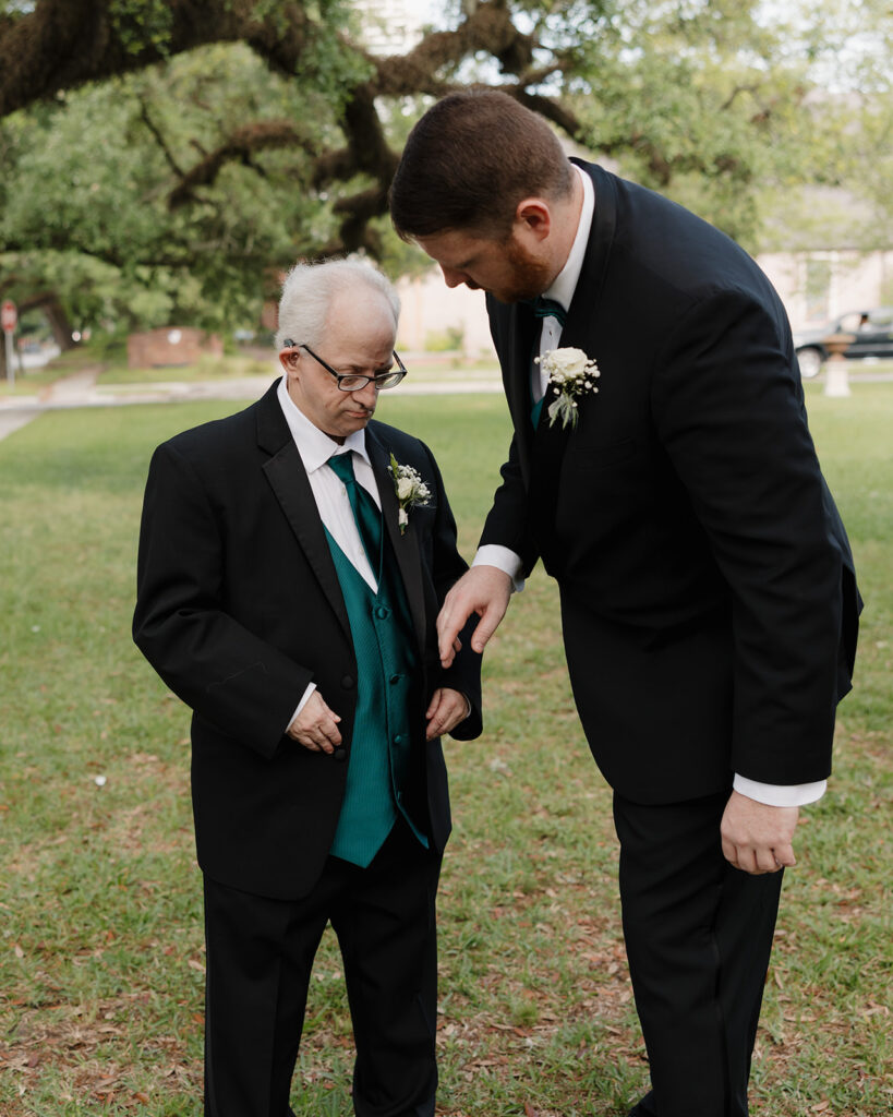 groom assists his brother with buttoning his jacket