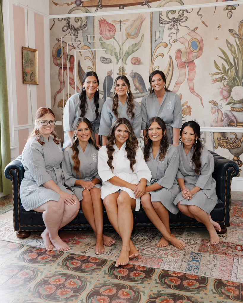 bride and bridesmaids sit on an antique couch