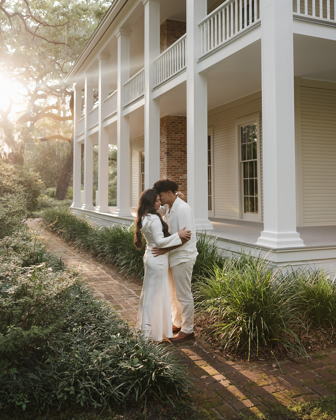 man and woman kiss besides the Wesley mansion at Eden Gardens State Park