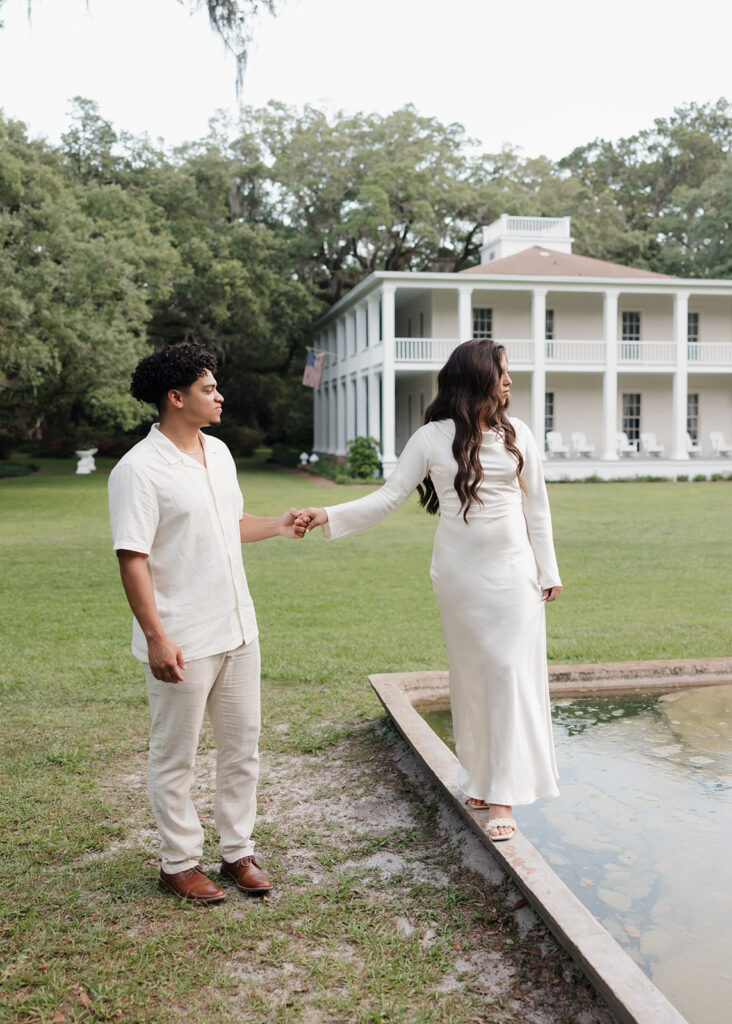 woman balances on a fountain while man leads her at Eden Gardens State Park