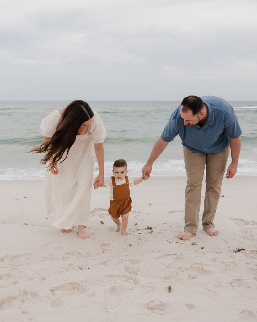 mother and father walk along the shore on Pensacola Beach