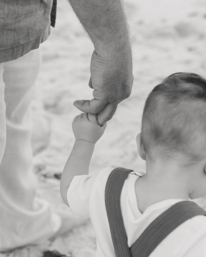 grandpa holds grandbaby's hand