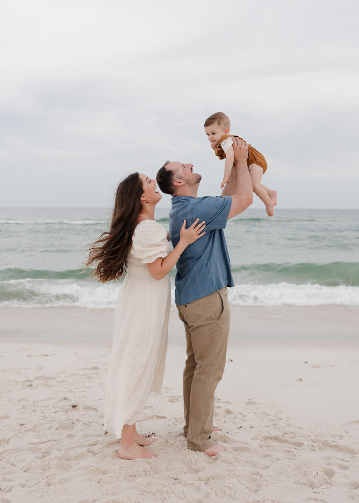 dad lifts baby in the air and mom smiles at him