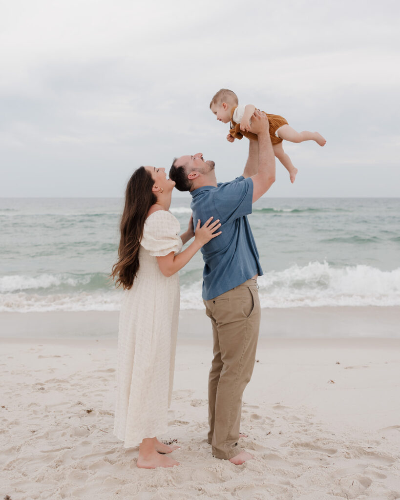 dad lifts baby in the air and mom smiles at him