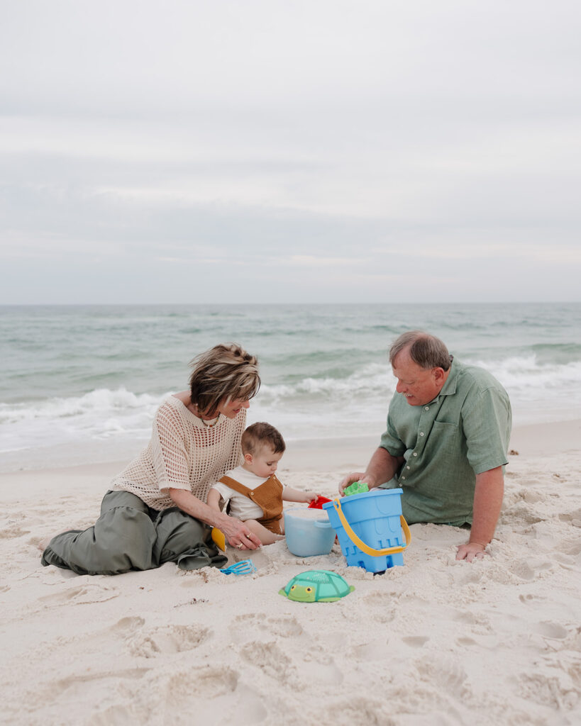 grandparents and grandson build a sandcastle on Pensacola Beach