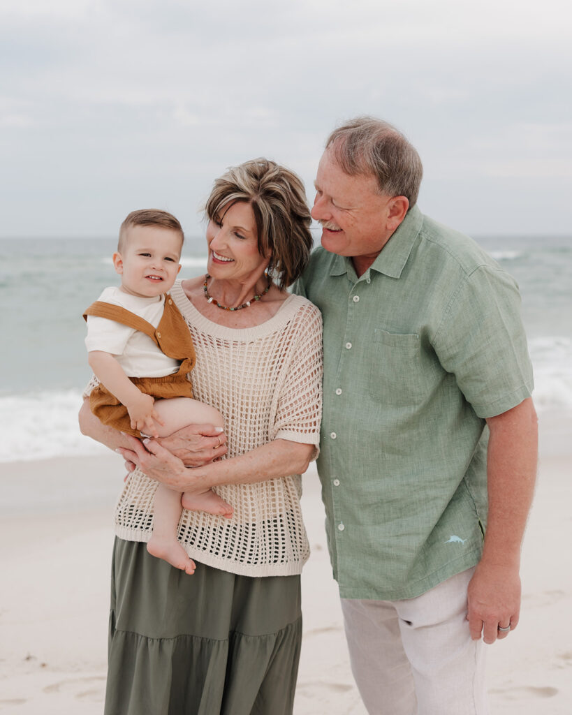 grandparents hold their grandson on Pensacola Beach