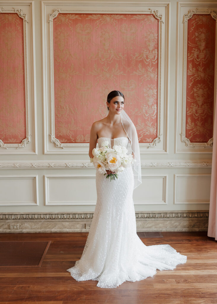 bride holds her bouquet and looks out the window