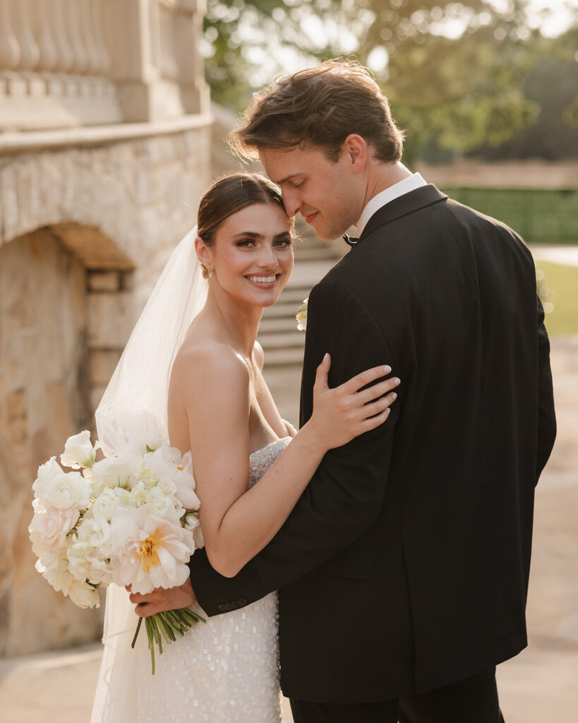 bride smiles as groom kisses her head