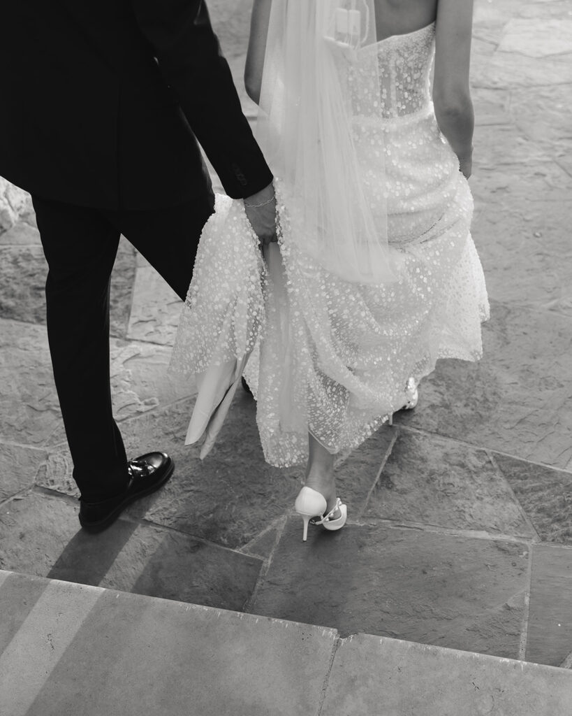 groom helps bride down staircase