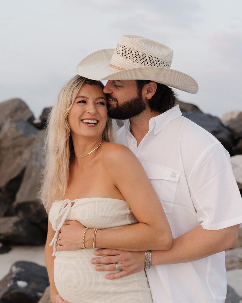 man kisses woman's head on Destin, Florida beach