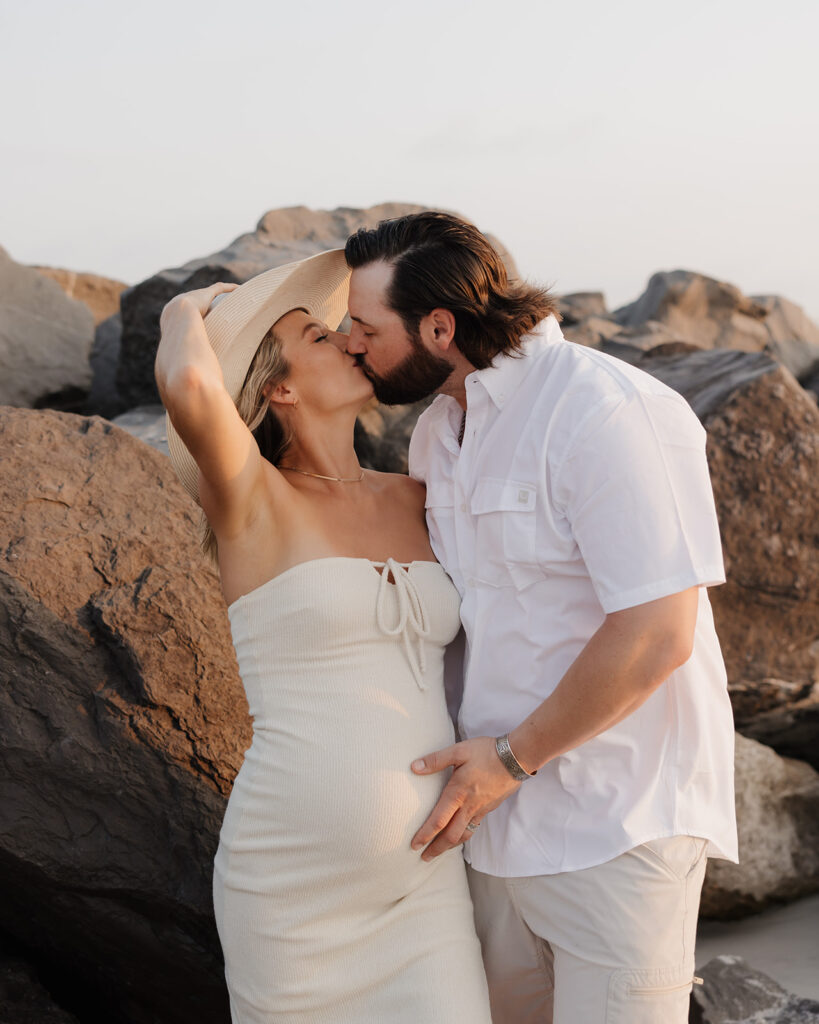 man kisses woman while touching her pregnant belly