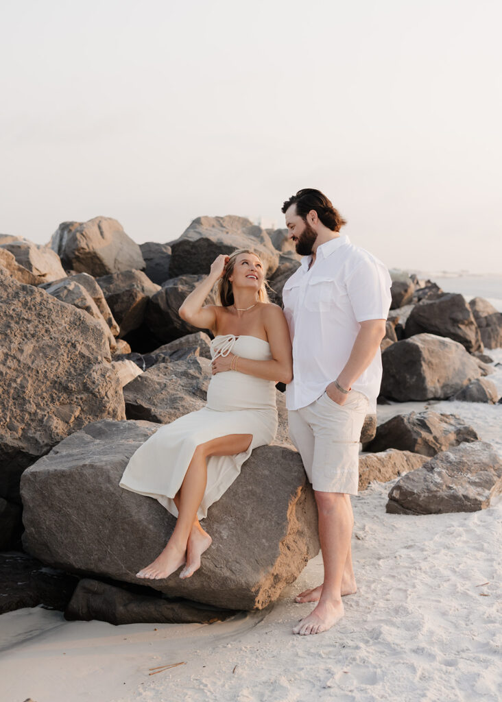 woman sits on a rock and smiles at her husband