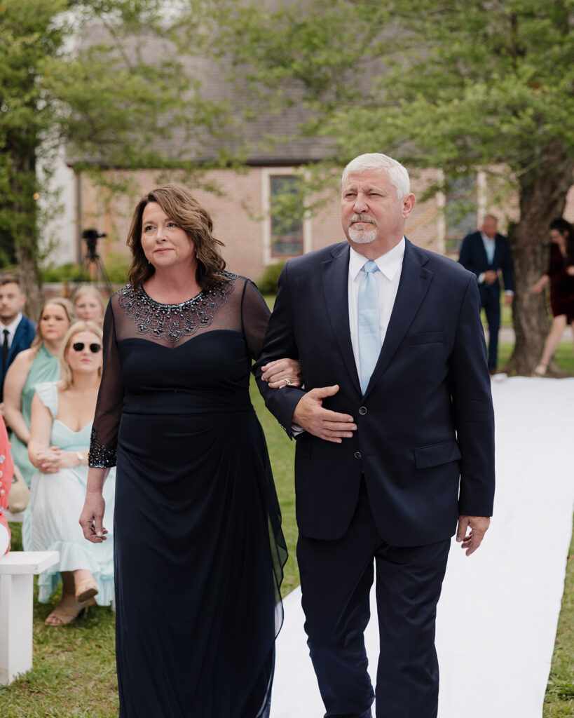 parents of the groom walk down the aisle
