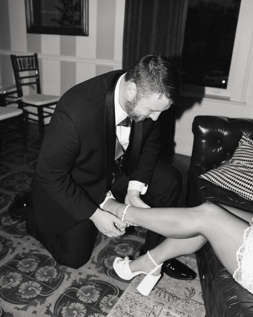 groom puts bride's shoes on her feet