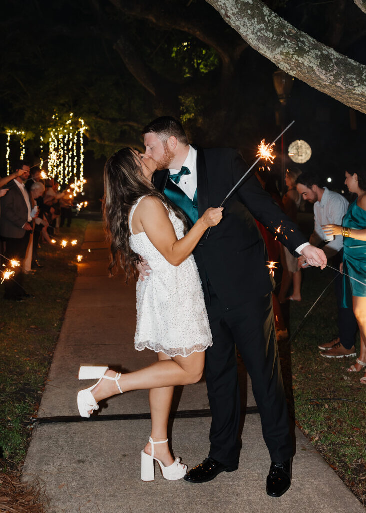 bride and groom kiss under a tunnel of sparklers