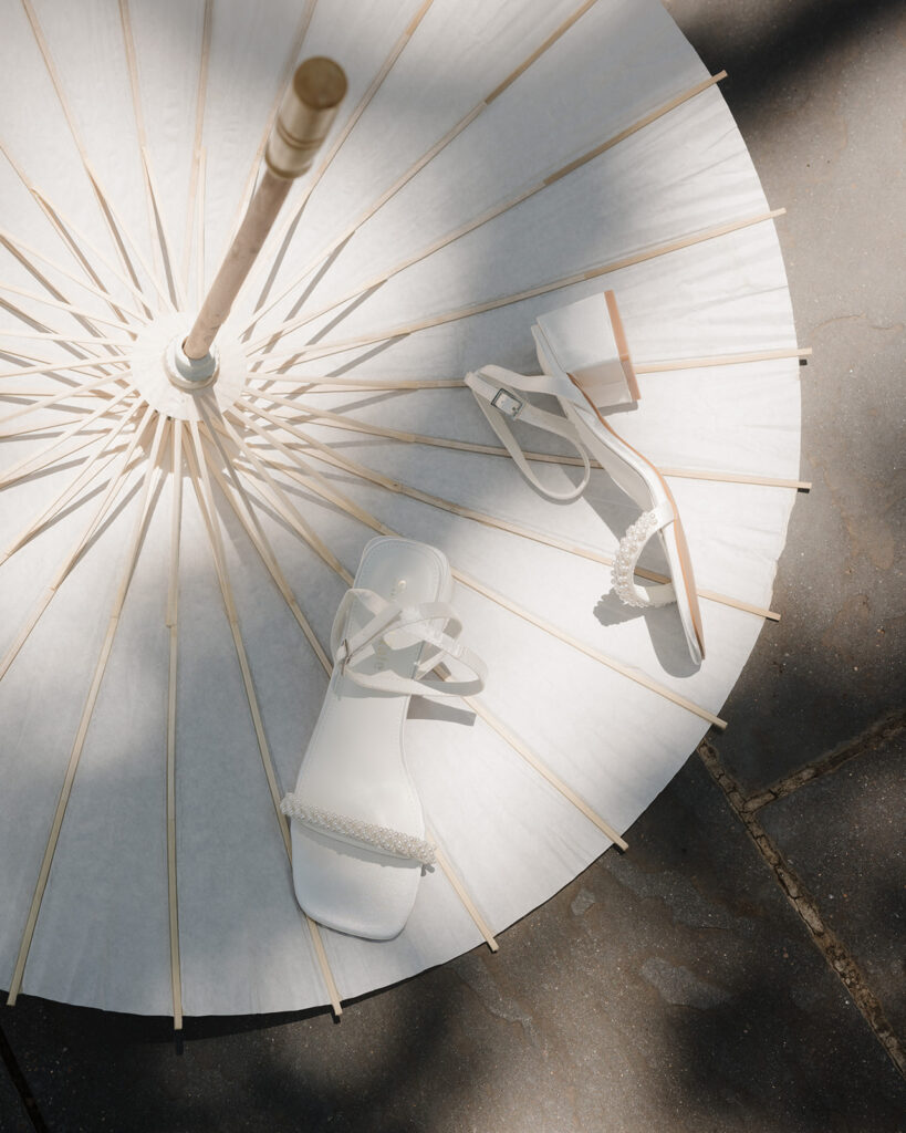 bride's wedding heels sit on top of a white parasol