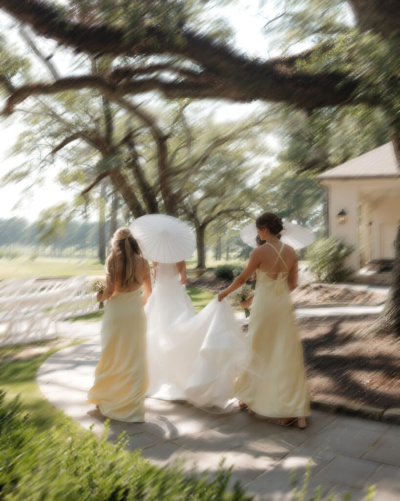 bride and bridesmaids walk while holding a parasol