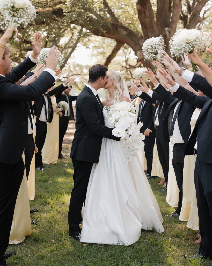 bride and groom kiss as the wedding party cheers