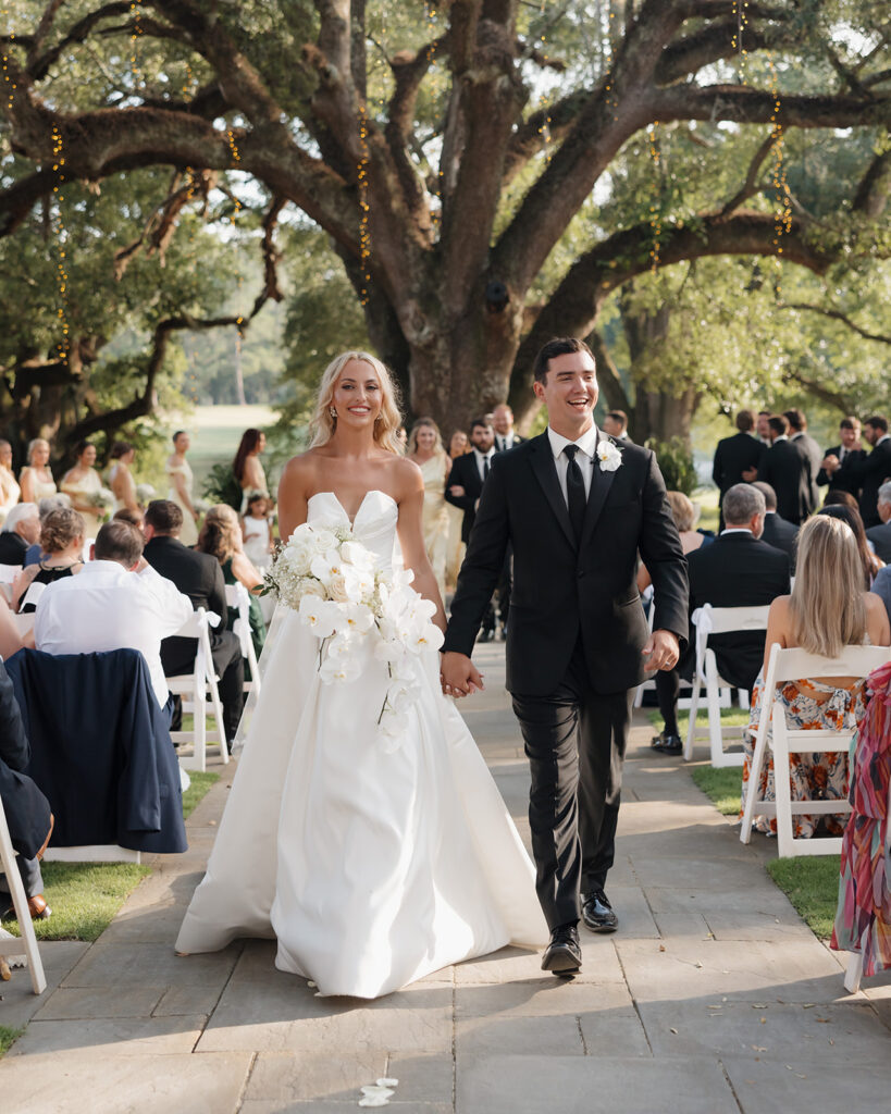 bride and groom celebrate while walking down the aisle