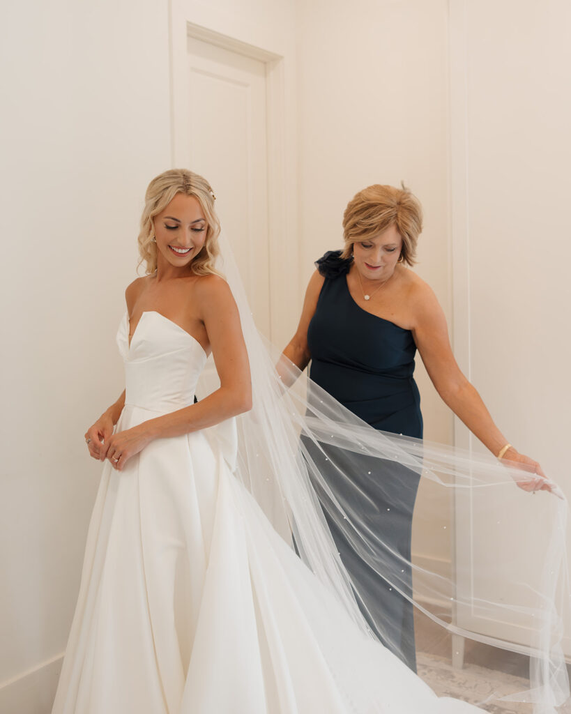 bride's mother helps her put on her wedding veil