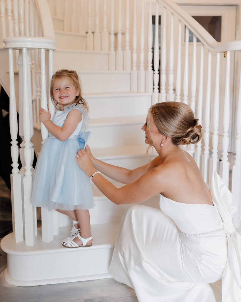 bride helps flower girl into her dress