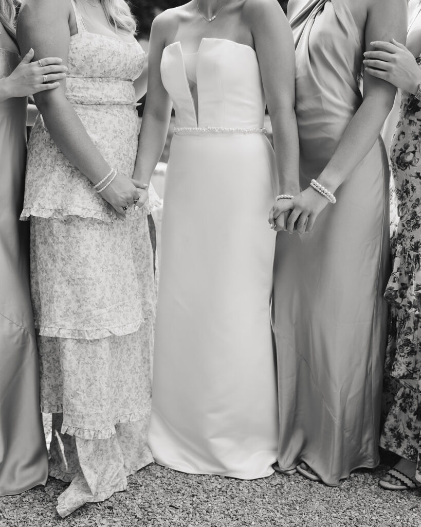 bride holds hands with her bridesmaids