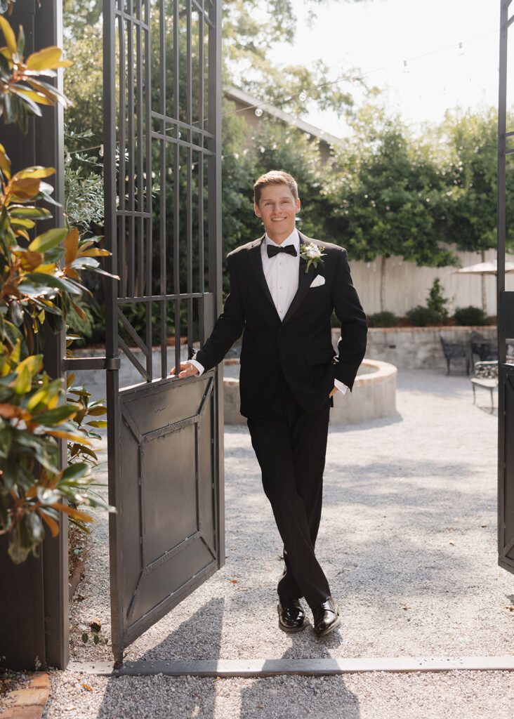 groom stands in the middle of an open gate