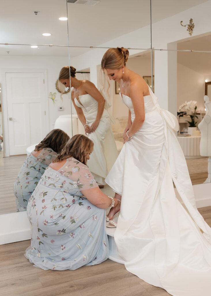 mother of the bride helps the bride put on her heels