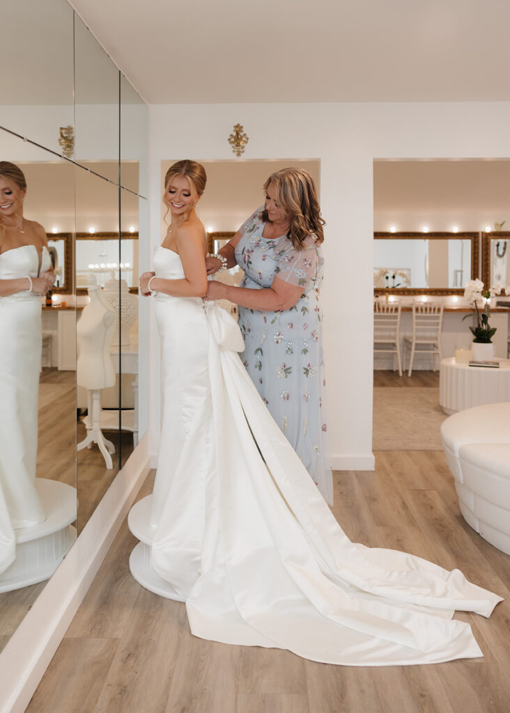 mother of the bride helps bride into her wedding dress