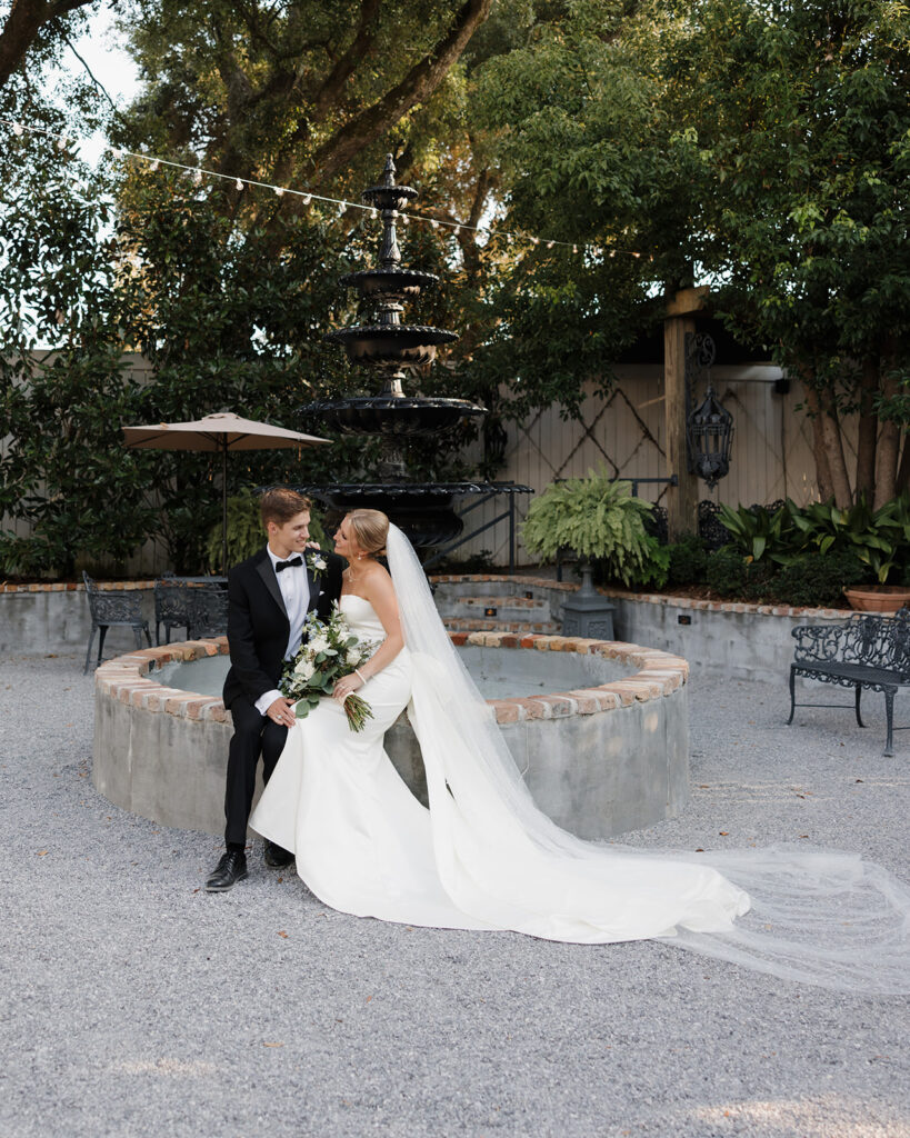 bride and groom sit by a fountain