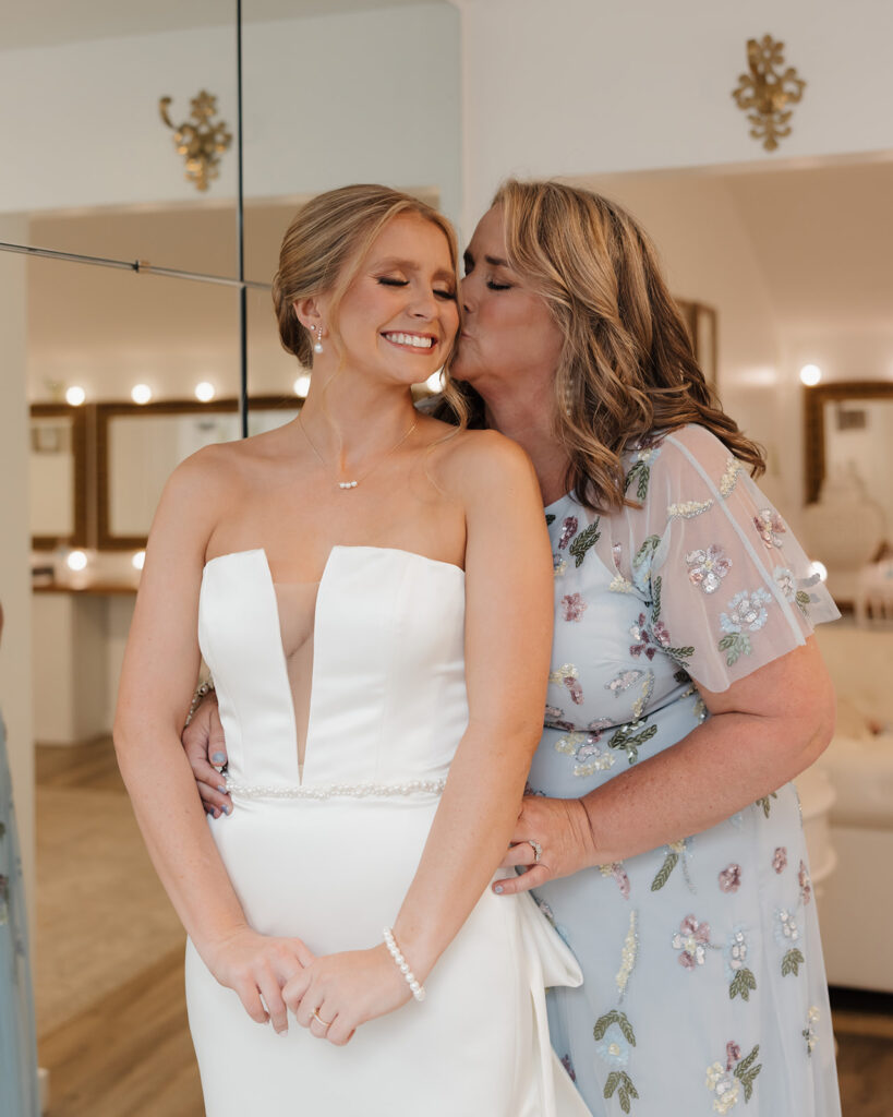 mother of the bride kisses bride on the cheek