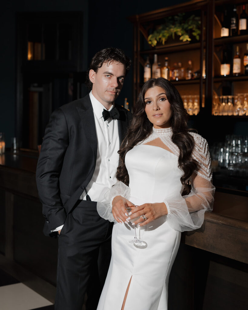 bride and groom pose by a bar