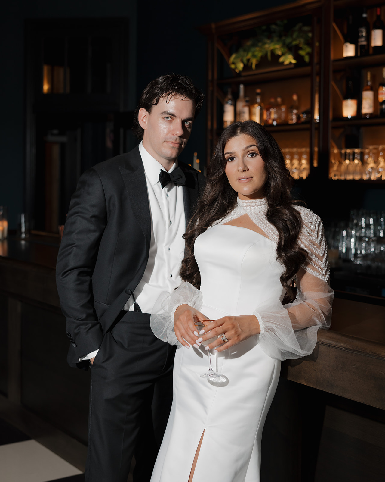 Bride and groom lean against a bar